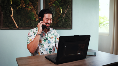 Man sitting at desk using a phone, laptop and tablet to work