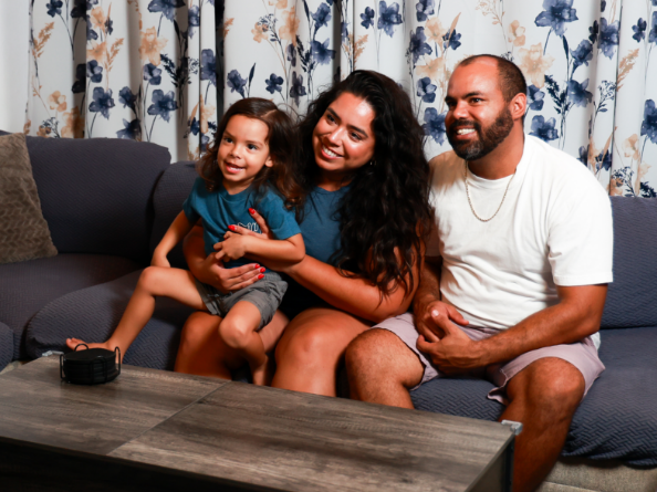 A son, mother and father sitting on a couch watching tv